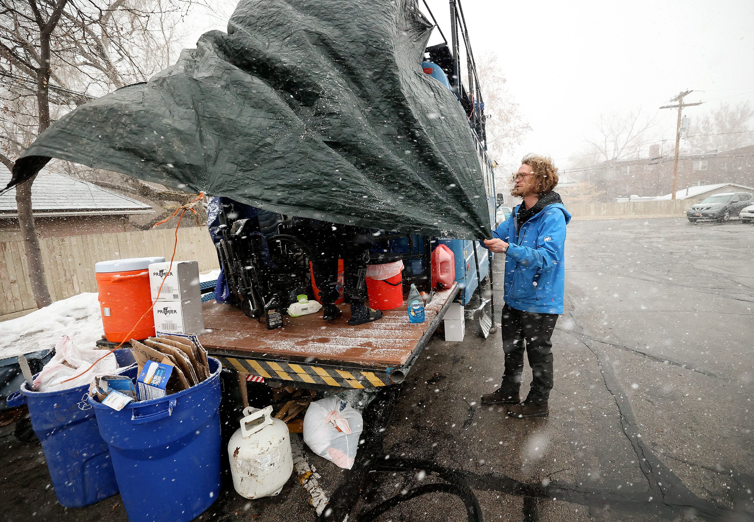Volunteer Taylor Burke tries to secure a tarp during a windy snow storm so that an unsheltered female will be able to have some privacy in the designated bathroom area on the back of the Nomad Alliance bus, parked outside a meetinghouse of The Church of Jesus Christ of Latter-day Saints that is not in use on March 8.
