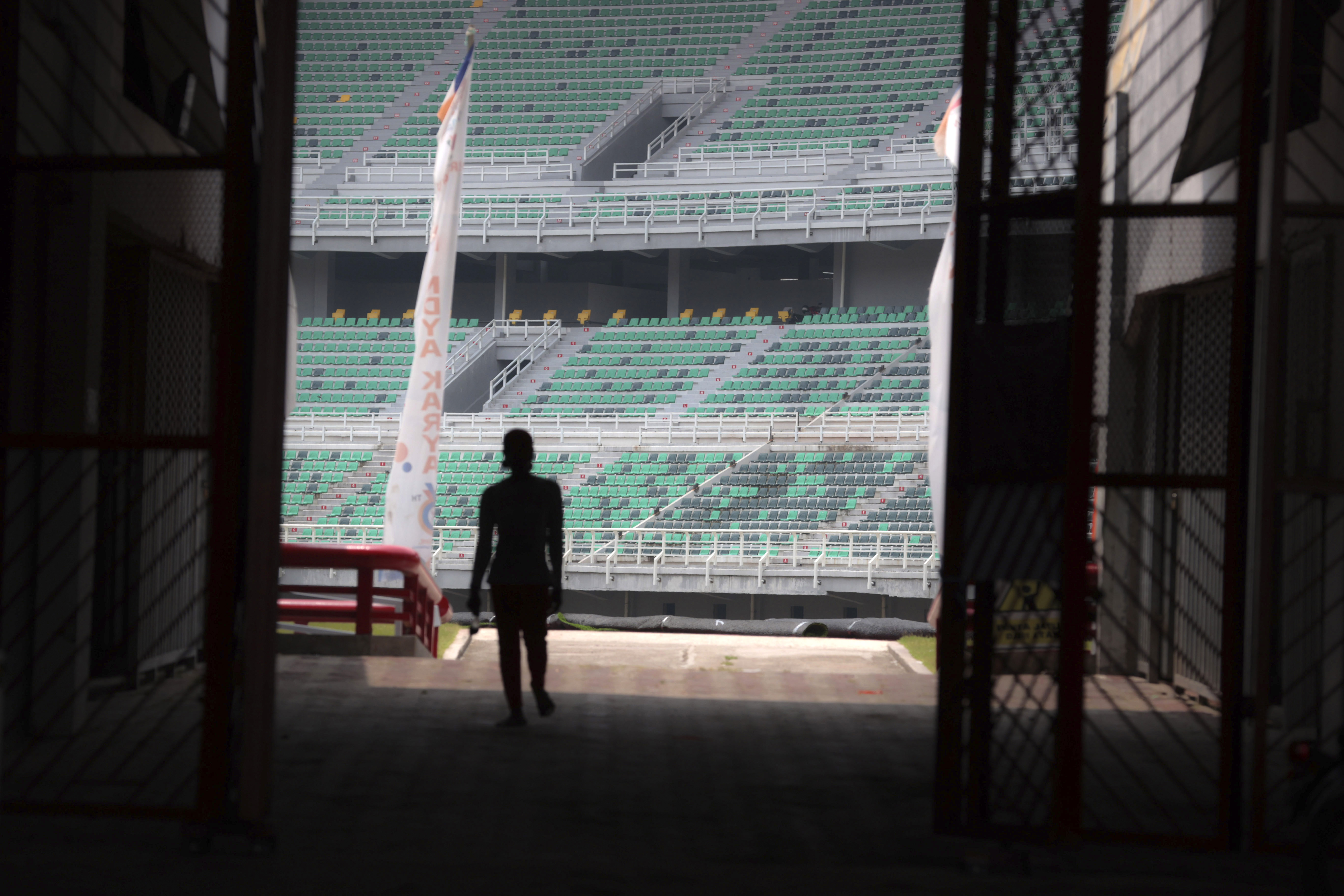 A worker is silhouetted against spectators seats at Gelora Bung Tomo Stadium, one of the venues prepared to host FIFA U-20 World Cup, in Surabaya, East Java, Indonesia, Thursday, March 30, 2023. Indonesia was stripped of hosting rights for the Under-20 World Cup on Wednesday only eight weeks before the start of the tournament amid political turmoil regarding Israel's participation.