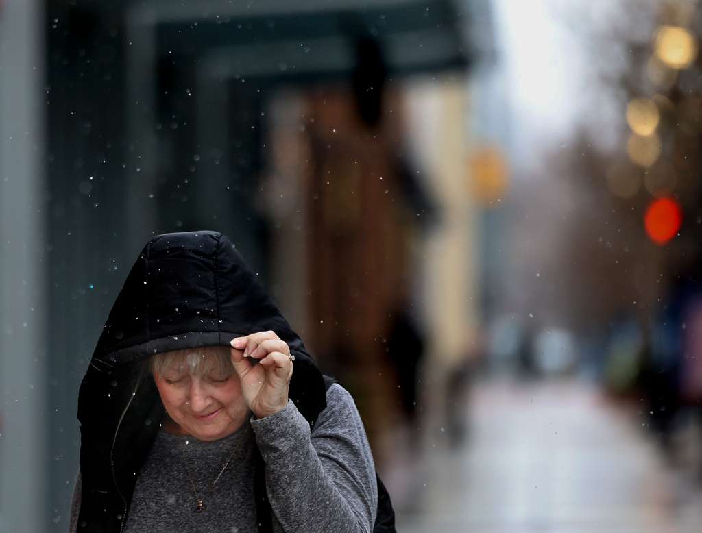 Sheila Thompson protects her face from a light snowfall while walking in Salt Lake City on Thursday.