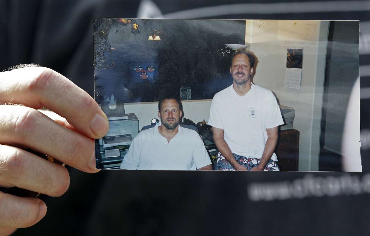 In this Oct. 2, 2017 photo, Eric Paddock holds a photo of himself, at left, and his brother, Las Vegas shooter Stephen Paddock, at right, outside his home in Orlando, Fla.