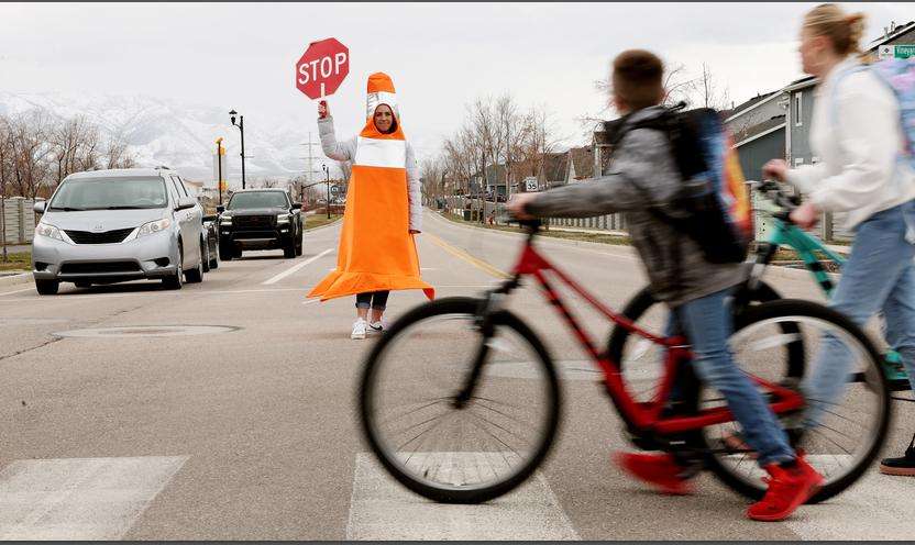Whitney Durfee works as a crossing guard outside Trailside Elementary School in Vineyard on Friday. Durfee started dressing as a traffic cone to raise awareness for the importance of avoiding distracted driving and speeding in school zones.
