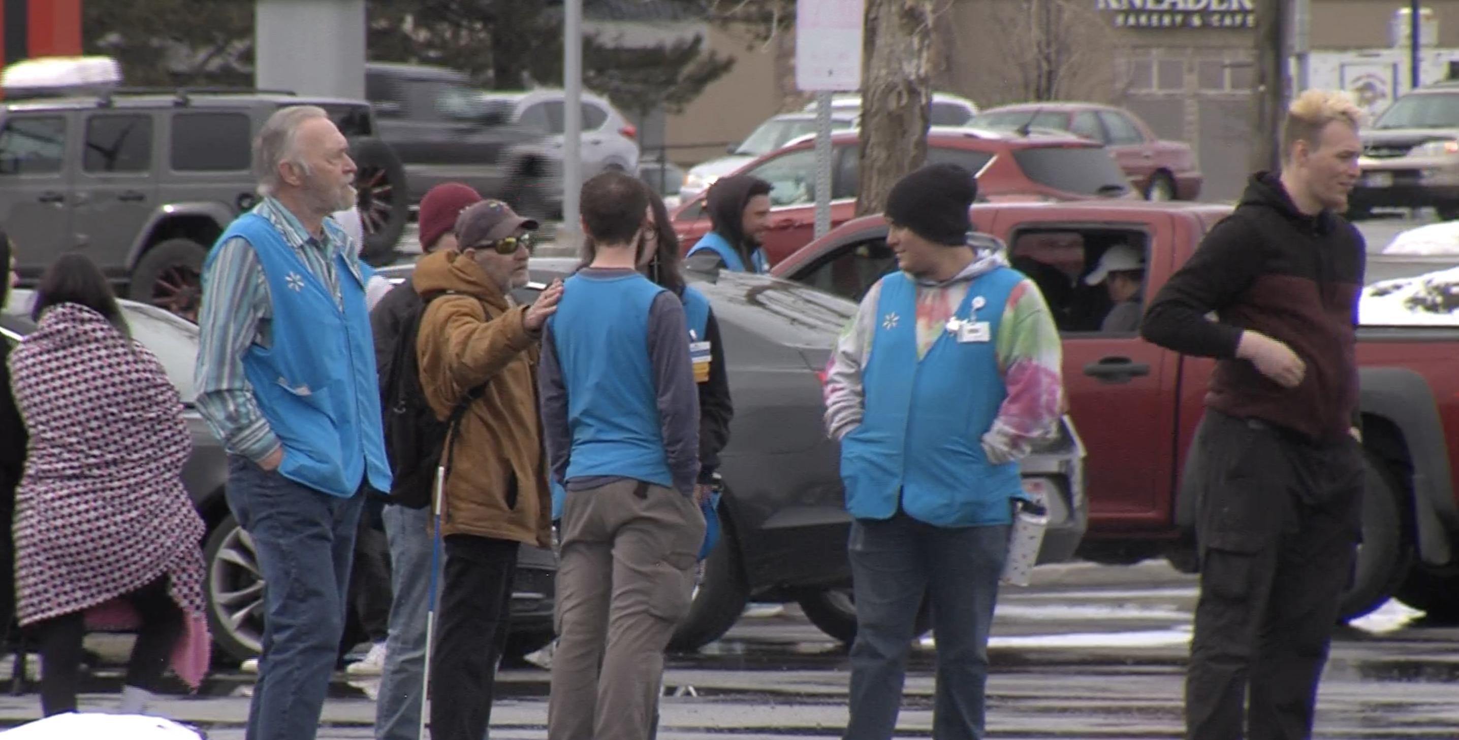 Employees stand outside the North Logan Walmart on Friday. The store was evacuated after a fake bomb, and police are asking the public to help identify the suspects.