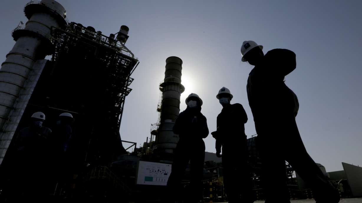 Saudi Aramco engineers walk in front of a gas turbine generator at Khurais oil field during a tour in Saudi Arabia on June 28, 2021. Saudi Arabia said Sunday it will cut oil production by 500,000 barrels per day from May until the end of 2023.