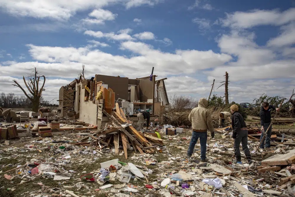 Family and neighbors look through debris on Ed Whestine's farm southwest of Wellman, Iowa on Saturday. Possibly dozens of tornadoes killed multiple people in small towns and big cities across the South and Midwest, tearing a path through the Arkansas capital, collapsing the roof of a packed concert venue in Illinois, and stunning people throughout the region Saturday with the damage's scope.