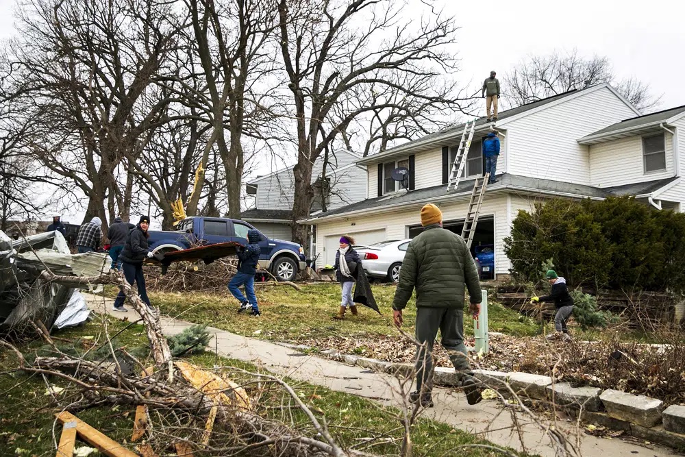 Meghann Foster, mayor of Coralville, Iowa, bottom right, works with community members to clean up storm damage on 23rd Avenue after a tornado, Saturday in Coralville, Iowa.
