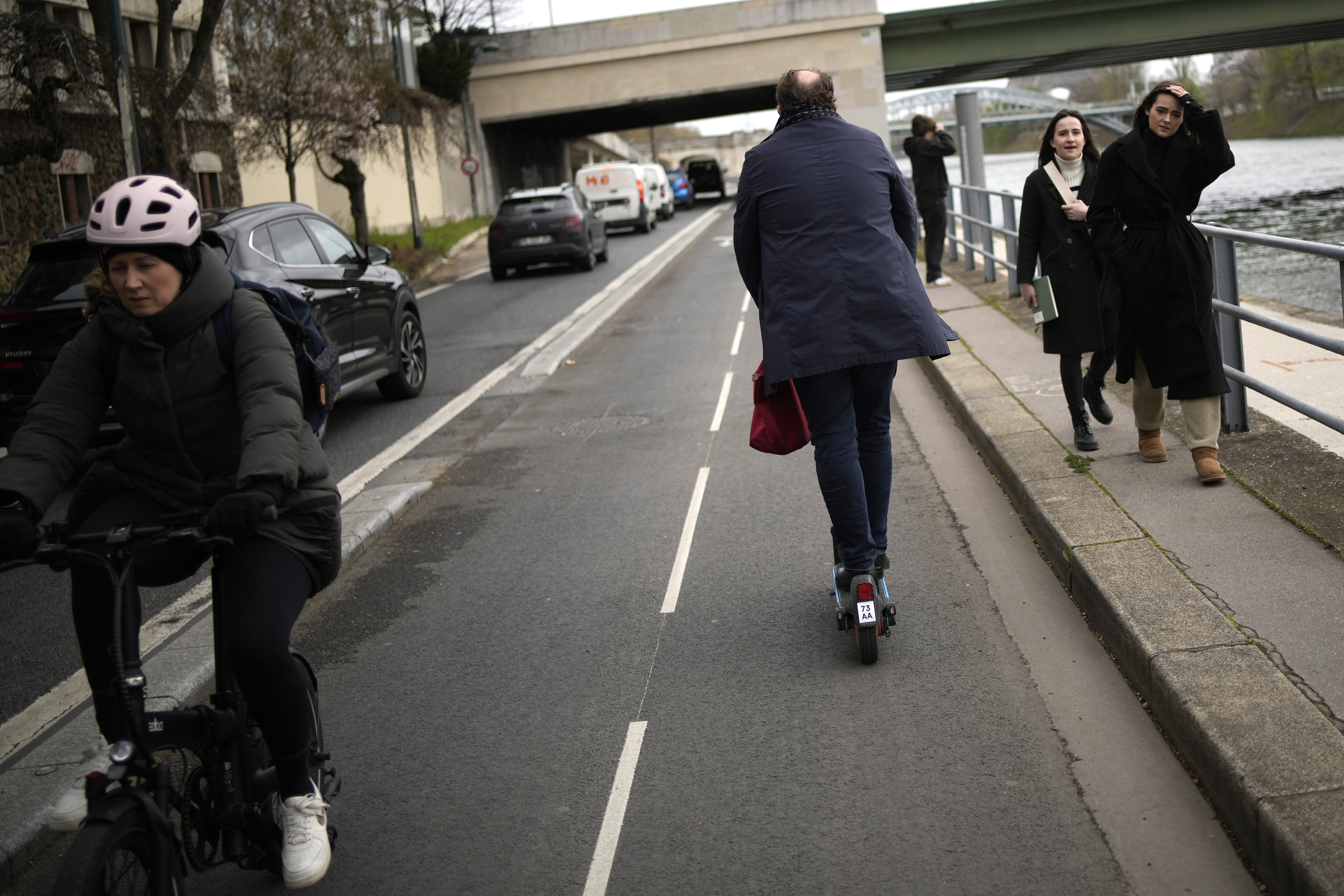 A man rides a scooter near the Seine river in Paris, Friday. Parisians have overwhelmingly voted to banish the French capital's ubiquitous for-hire electric scooters from their streets. 
