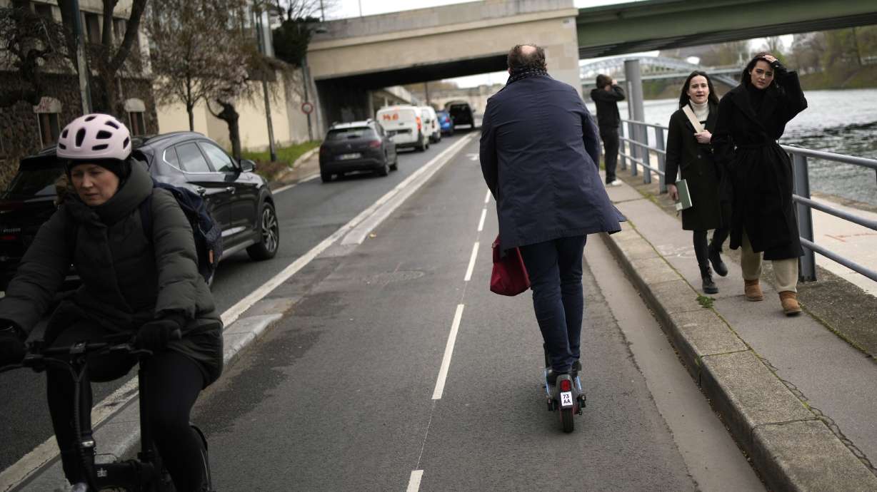 A man rides a scooter near the Seine river in Paris, Friday. Parisians have overwhelmingly voted to banish the French capital's ubiquitous for-hire electric scooters from their streets.