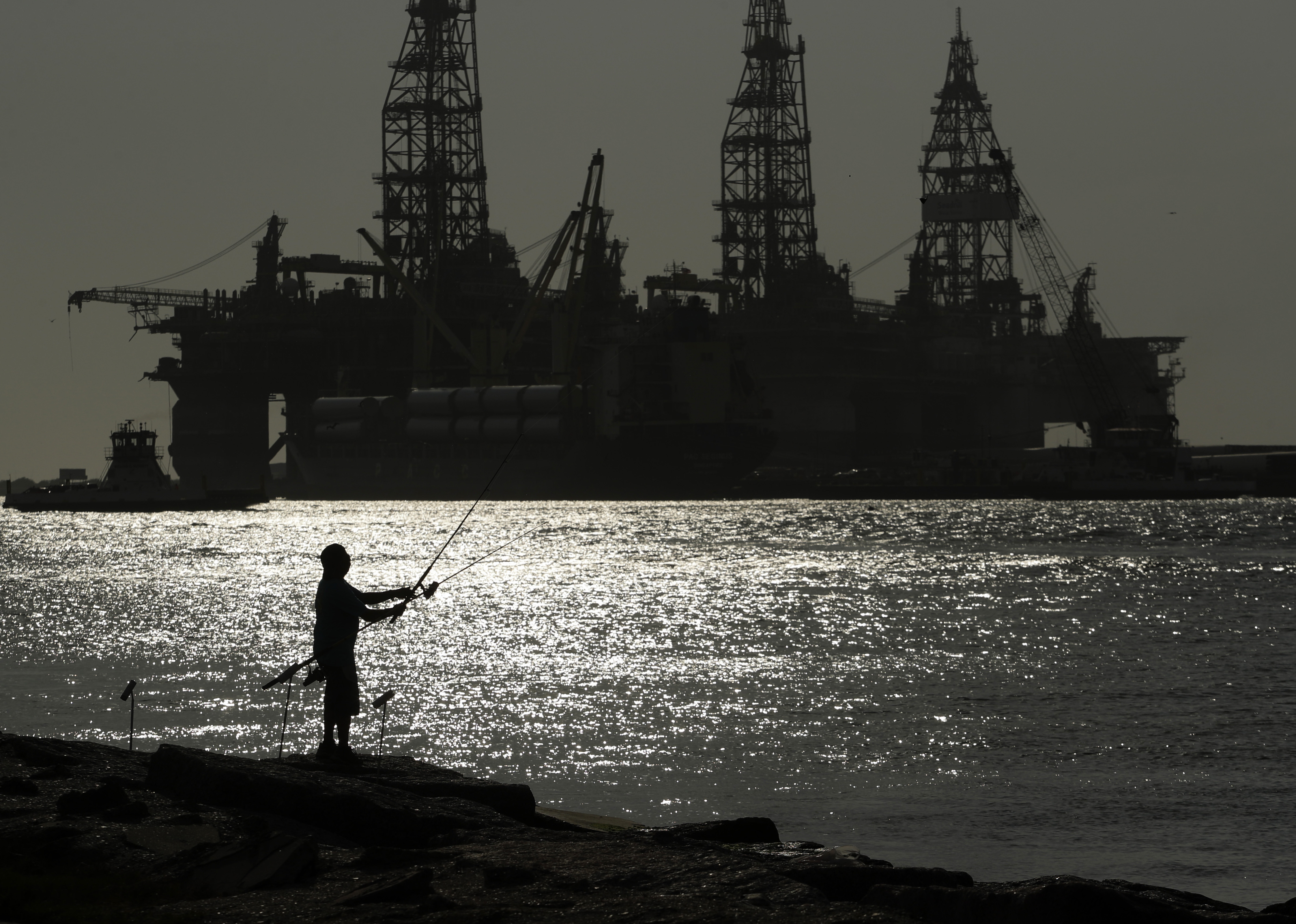 A man fishes near an oil drilling platform on May 8, 2020, in Port Aransas, Texas. Offshore oil and gas operations in the Gulf of Mexico are releasing far more climate-changing methane than official estimates show, according to a new study published Monday.