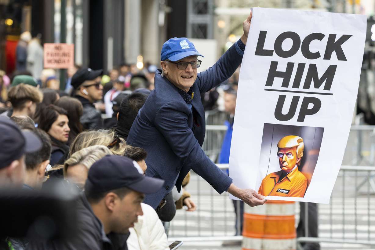 A protester holds a placard outside Trump Tower in New York on Monday. Former President Donald Trump is expected to be booked and arraigned on Tuesday on charges arising from hush money payments during his 2016 campaign.