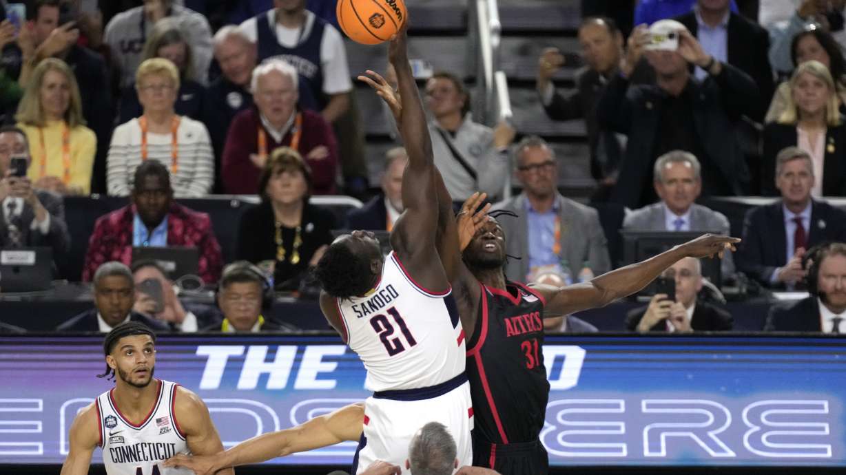 Connecticut forward Adama Sanogo (21) and San Diego State forward Nathan Mensah (31) fight for the opening tip during the first half of the men's national championship college basketball game in the NCAA Tournament on Monday, April 3, 2023, in Houston.