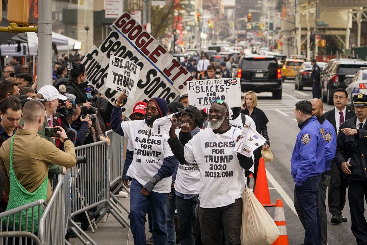 Supporters of former President Donald Trump parade their signs in front of assembled media and onlookers outside Manhattan Criminal Court, Tuesday, in New York. Trump surrendered in Manhattan on Tuesday to face criminal charges stemming from 2016 hush money payments.