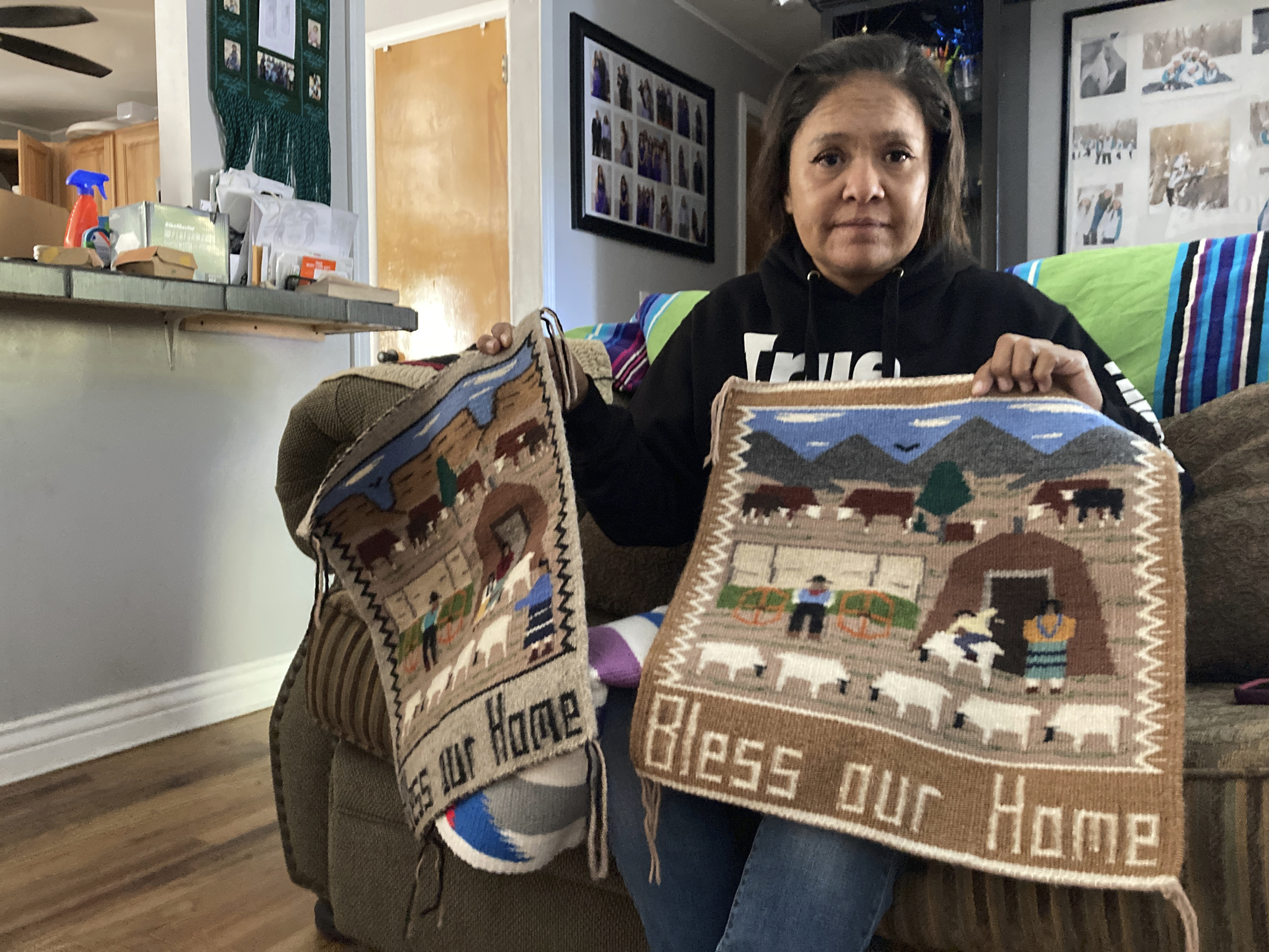 Seraphine Warren poses for a photo in her home in Tooele, Utah, on Sept. 23, 2021, with a rug made by her aunt, Navajo rug weaver Ella Mae Begay. A federal grand jury has indicted a New Mexico man on assault and carjacking charges in connection with the 2021 disappearance of Begay.