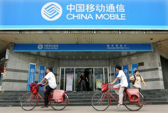 Chinese cyclists pedal past a China Mobile office in Beijing Aug. 10, 2005.