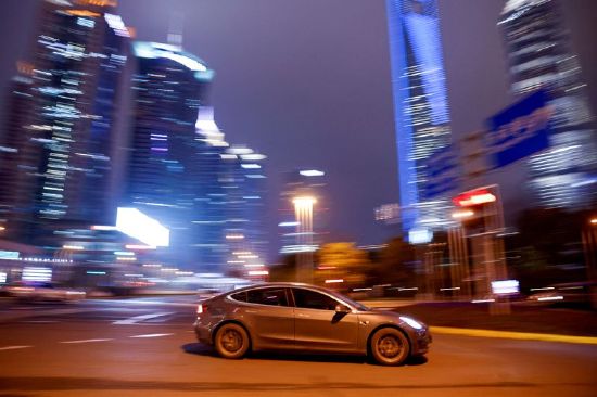 A Tesla electric vehicle drives past a crossing in Shanghai, China March 9, 2021.