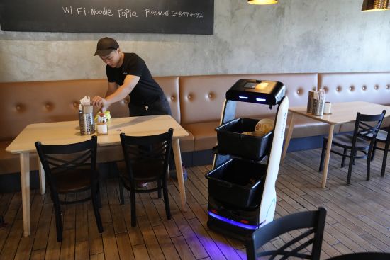 A BellaBot robot at the Noodle Topia restaurant heads back to the kitchen after a table is cleared on March 20 in Madison Heights, Mich. Sales of robot servers have been growing rapidly in recent years, and tens of thousands of robots are now gliding through dining rooms worldwide.