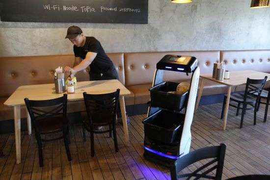 A BellaBot robot at the Noodle Topia restaurant heads back to the kitchen after a table is cleared on March 20 in Madison Heights, Mich. Sales of robot servers have been growing rapidly in recent years, and tens of thousands of robots are now gliding through dining rooms worldwide.