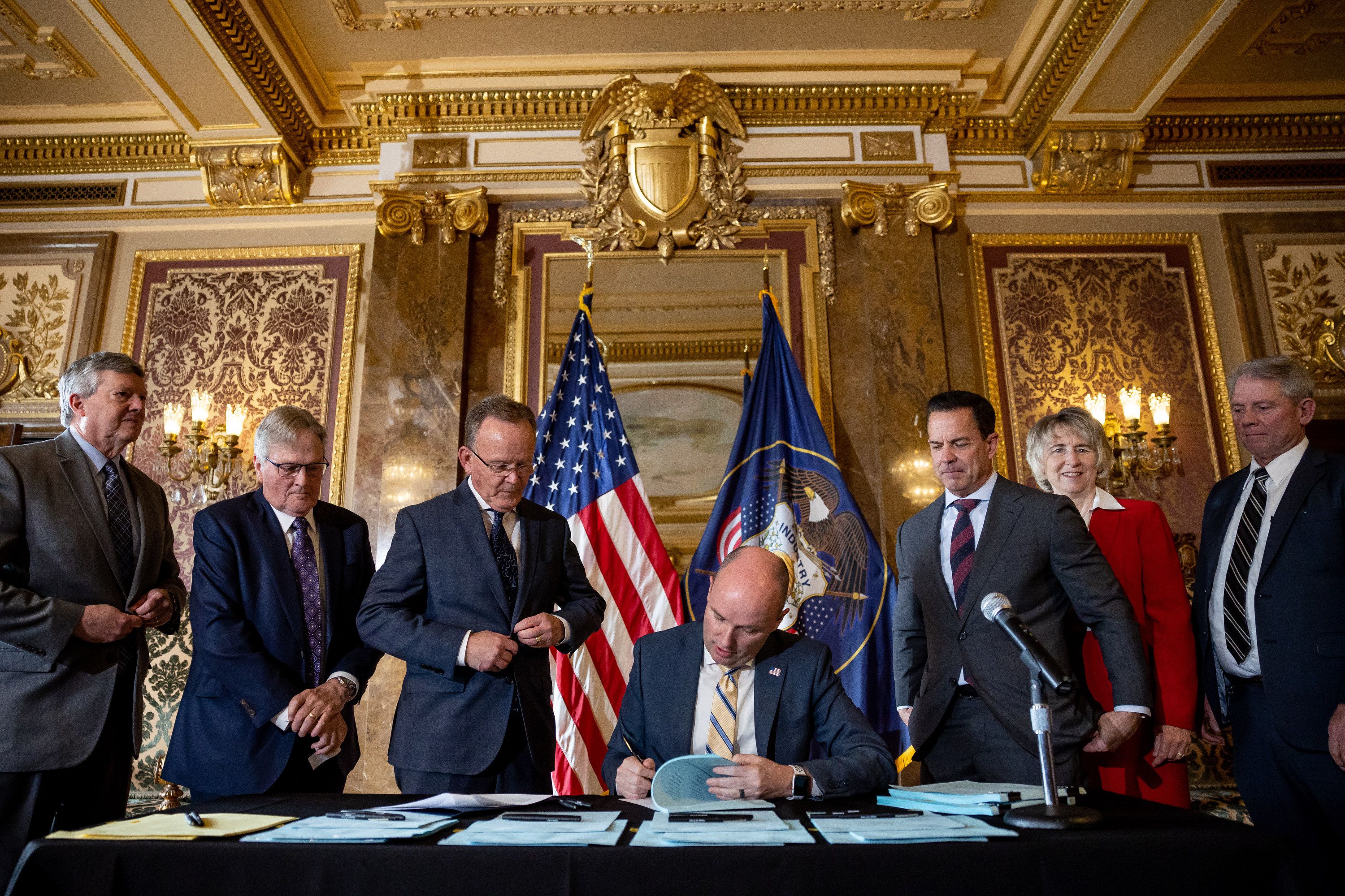Gov. Spencer Cox signs HB54, which provides $400 million in tax cuts, at the Capitol in Salt Lake City on Wednesday, March 22, 2023, as state legislative leaders look on.