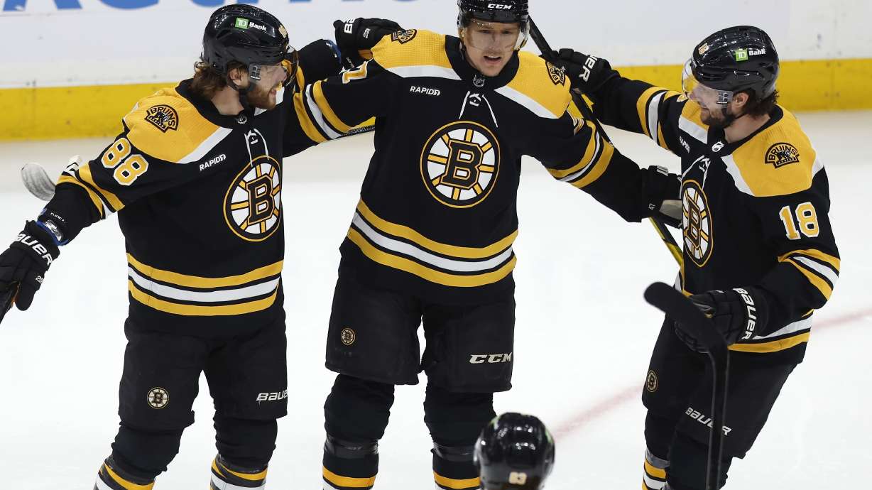 Boston Bruins' Pavel Zacha (18) celebrates with David Pastrnak (88), Hampus Lindholm (27) and Brad Marchand (63) after his first goal during the first period of the team's NHL hockey game against the New Jersey Devils, Saturday, April 8, 2023, in Boston.