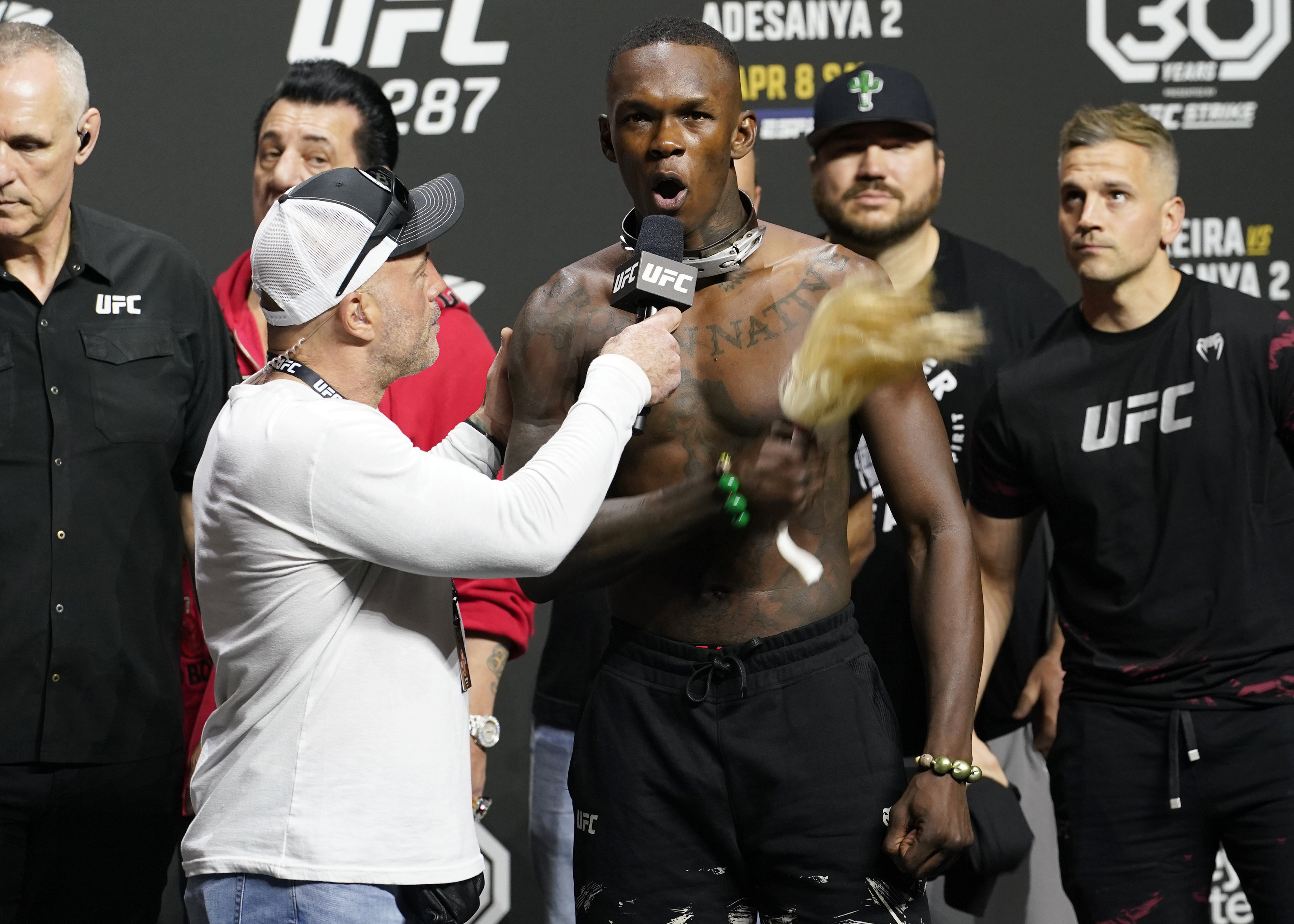 UFC commentator Joe Rogan, front left, listens to Israel Adesanya after a ceremonial weigh-in Friday, April 7, 2023, in Miami. Adesanya will face UFC 287 middleweight champion Alex Pereira on Saturday. 