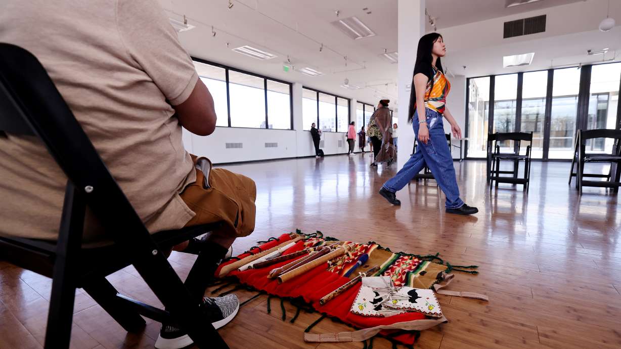 Rhianna Russell, walks past Aldean Ketchum as he plays a flute during rehearsal for an upcoming Indigenous fashion show at the Leonardo Museum in Salt Lake City on Sunday.