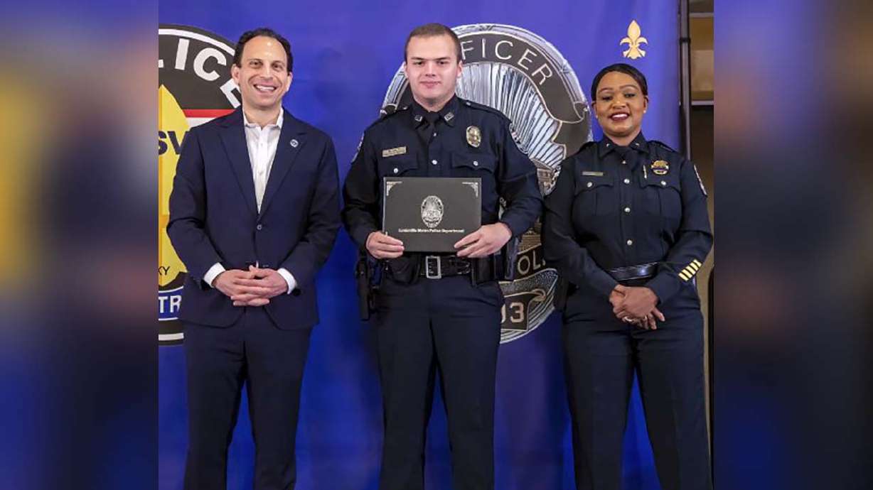 From left, Louisville Mayor Craig Greenberg, Officer Nickolas Wilt and Louisville Metro Interim Police Chief Jacquelyn Gwinn-Villaroel pose for a photo, in Louisville, Ky., March 31. Wilt was shot while responding to a call where a bank employee armed with a rifle opened fire at his workplace early Monday.