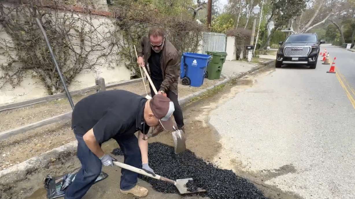 Former California Governor Arnold Schwarzenegger, center back, repairs a pot hole on a street in his Los Angeles neighborhood on Tuesday. Fed up by the pothole, Schwarzenegger filled it himself.