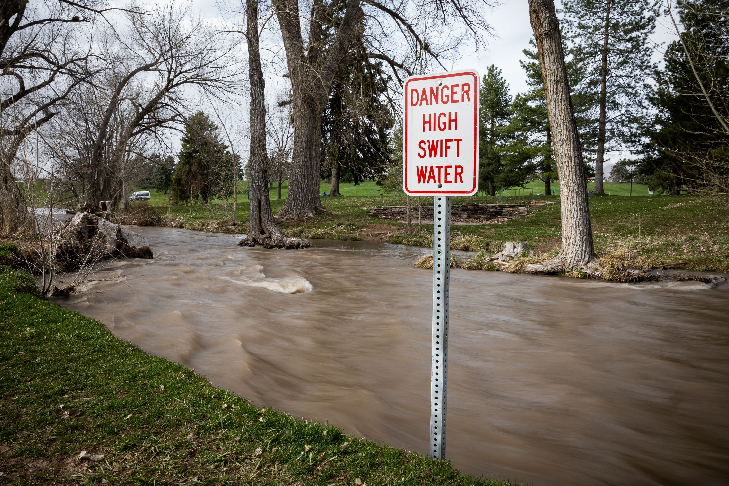 Signs warn people of dangerous conditions as spring snowmelt has swollen Parleys Creek where it runs through Sugar House Park in Salt Lake City on Wednesday.