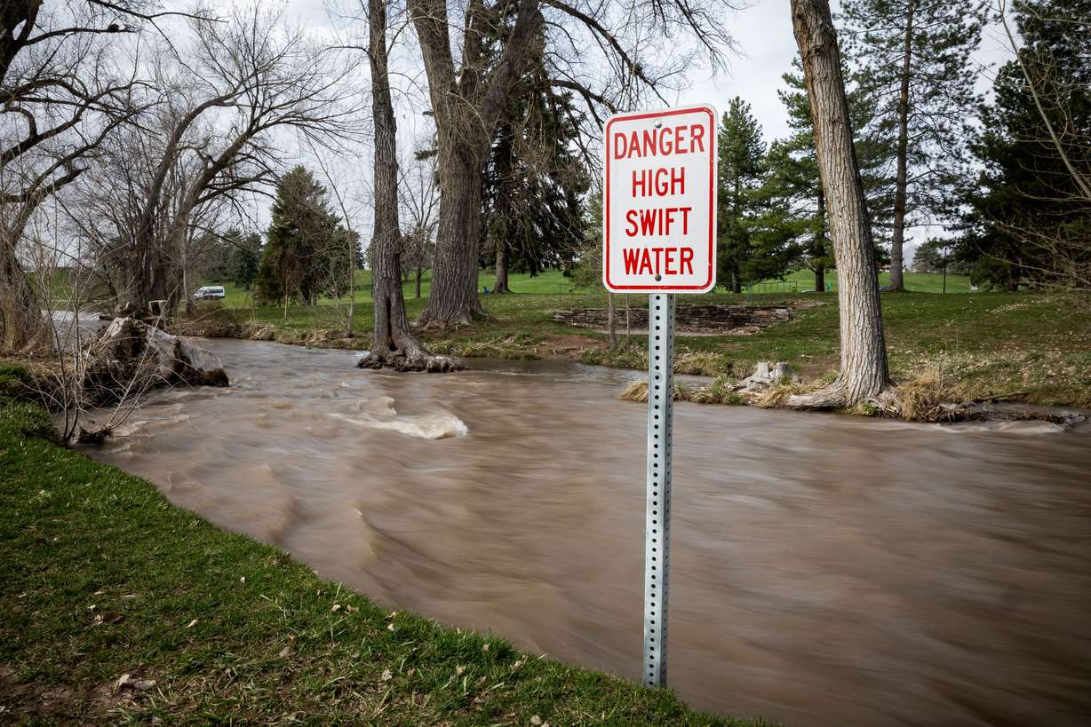 Signs warn people of dangerous conditions as spring snowmelt has swollen Parleys Creek where it runs through Sugar House Park in Salt Lake City on Wednesday.