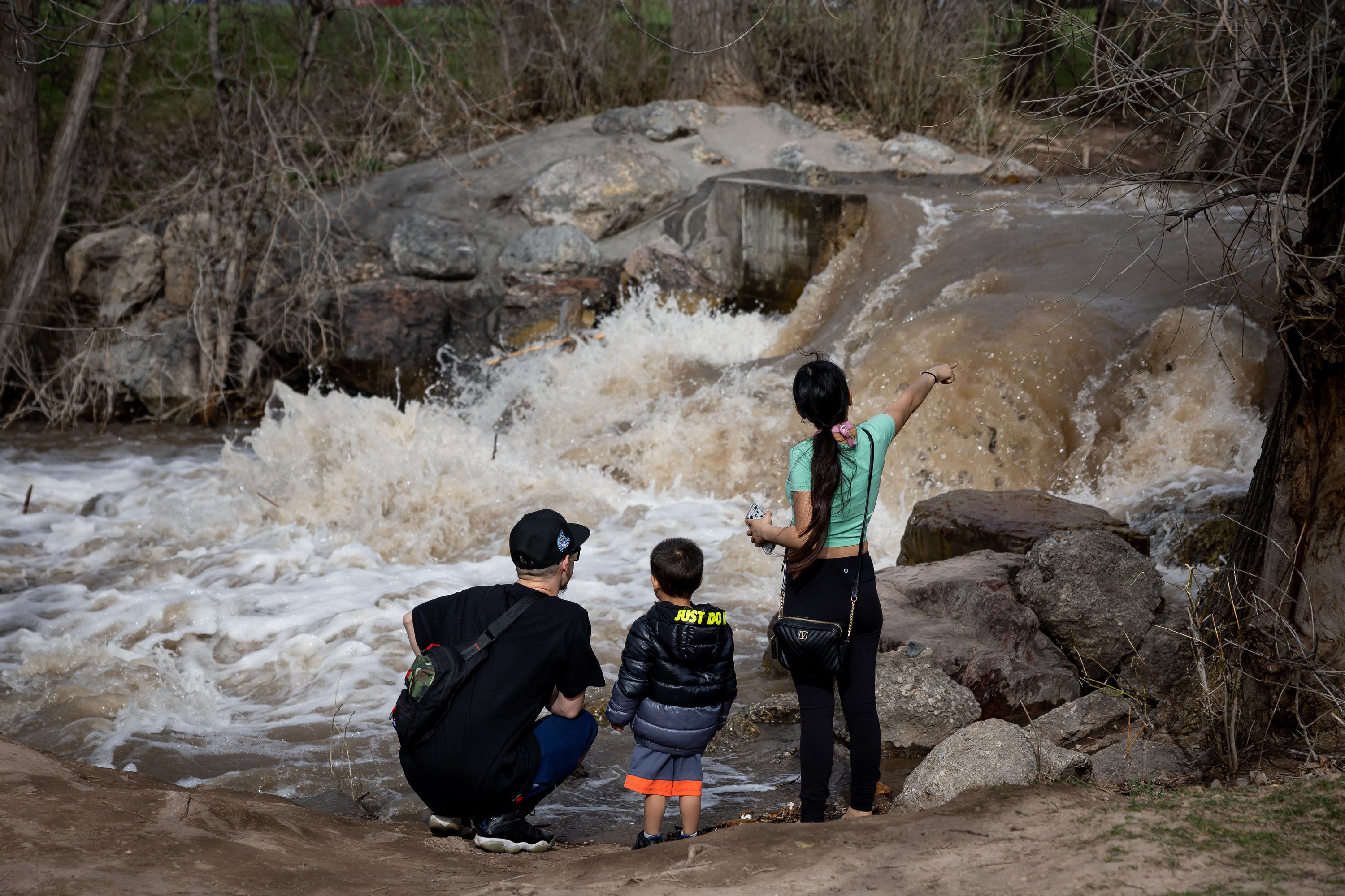 Angelo Florentino, Janin Quezada and their son Isaiah Florentino-Quezada, 3, pause to look at Parleys Creek swollen by spring snowmelt at Sugar House Park in Salt Lake City on Wednesday.