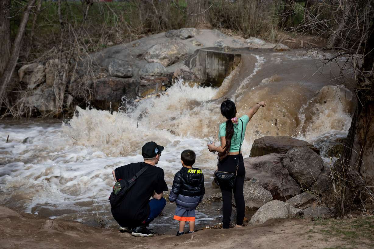 Angelo Florentino, Janin Quezada and their son Isaiah Florentino-Quezada, 3, pause to look at Parleys Creek swollen by spring snowmelt at Sugar House Park in Salt Lake City on Wednesday.