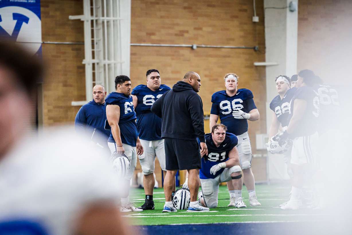 BYU defensive tackles coach Sione Po'uha talks with Jackson Cravens (91) and his teammates during spring practice, March 13, 2023 at the indoor practice facility in Provo.