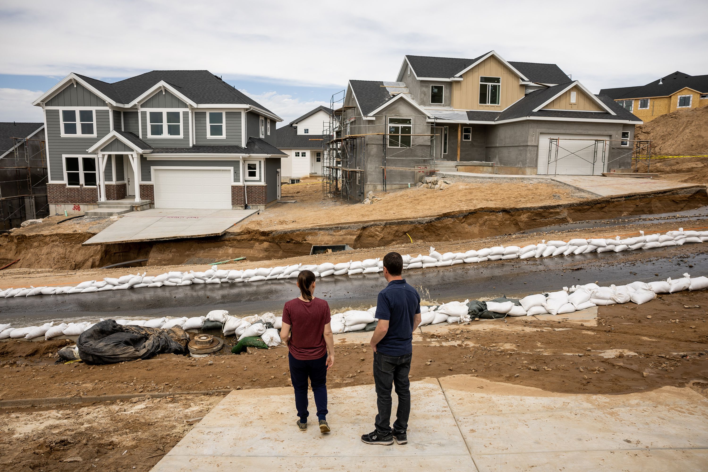 Kate and Jeff Harris stand on their driveway and survey damage from spring runoff on Orchard Ridge Lane in Kaysville on Wednesday. The couple just received the keys to their new home on the street one day earlier.