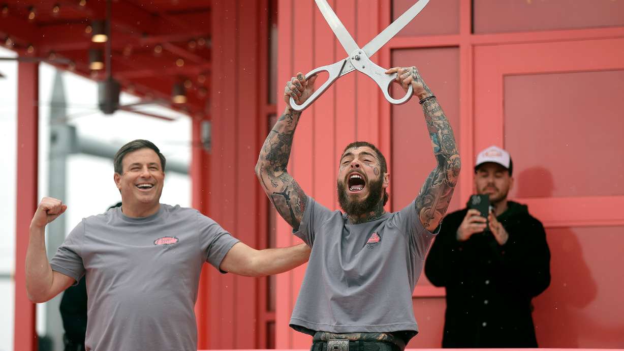 Raising Cane’s founder Todd Graves and Post Malone celebrate after cutting the ribbon during the grand reopening of a Raising Cane’s restaurant, designed by Post Malone, in Midvale on Thursday.