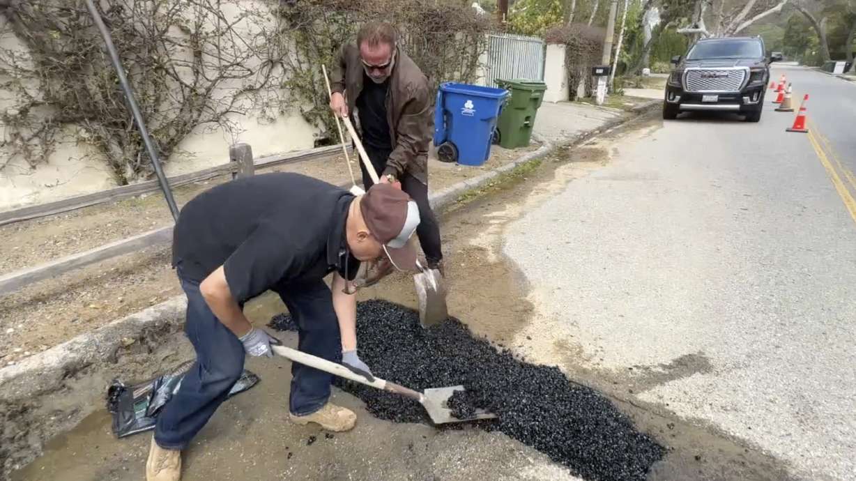 This video still image provided by The Office of Arnold Schwarzenegger, shows former California Governor Arnold Schwarzenegger, center back, repairing a pot hole on a street in his Los Angeles neighborhood on April 11. Fed up by an enormous pothole in his neighborhood, Schwarzenegger picked up a shovel and filled it himself.