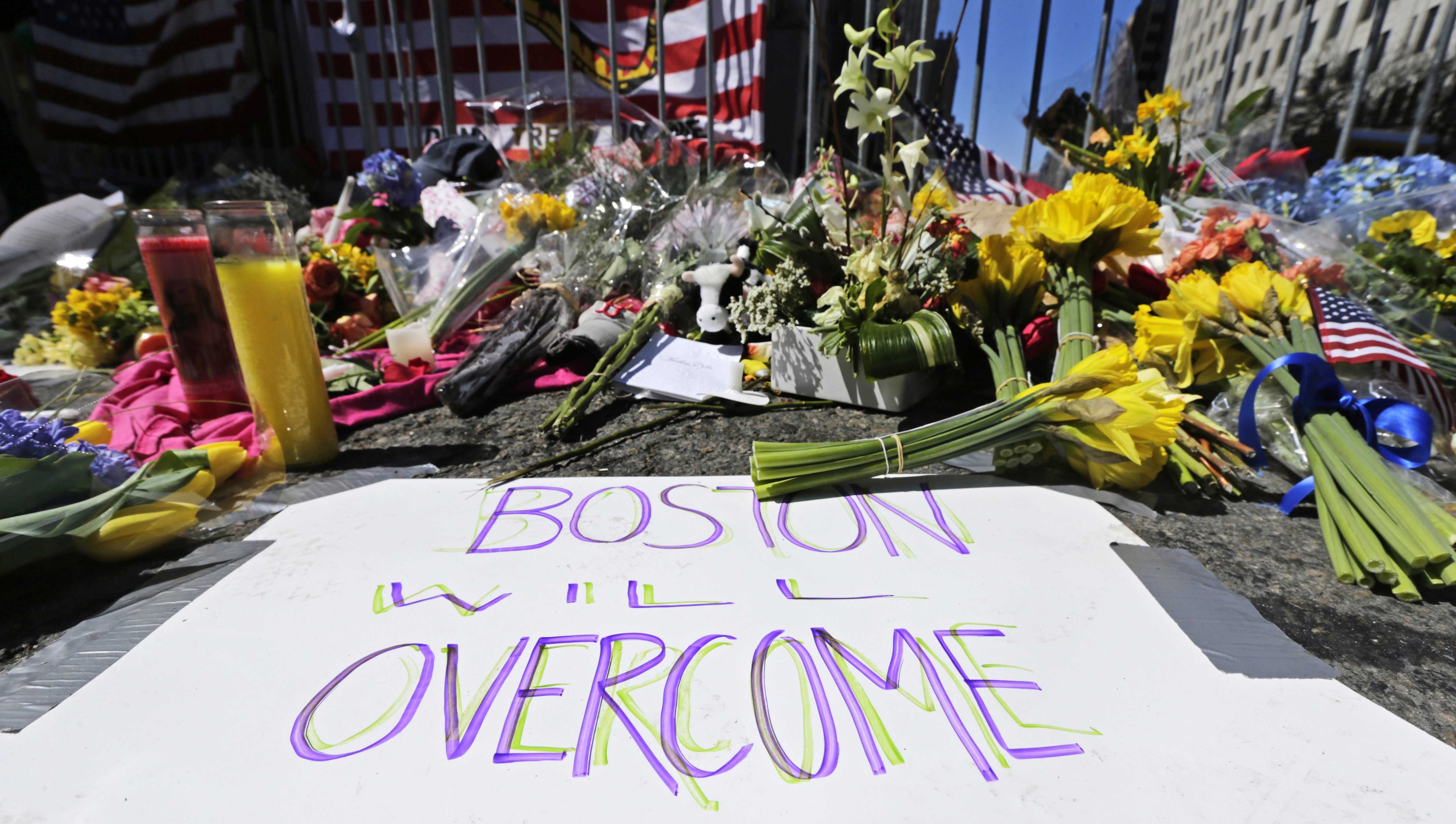 Flowers and signs adorn a barrier, two days after two explosions killed three and injured hundreds, near the finish line of the Boston Marathon at a makeshift memorial for victims and survivors of the bombing, April 17, 2013, in Boston. 