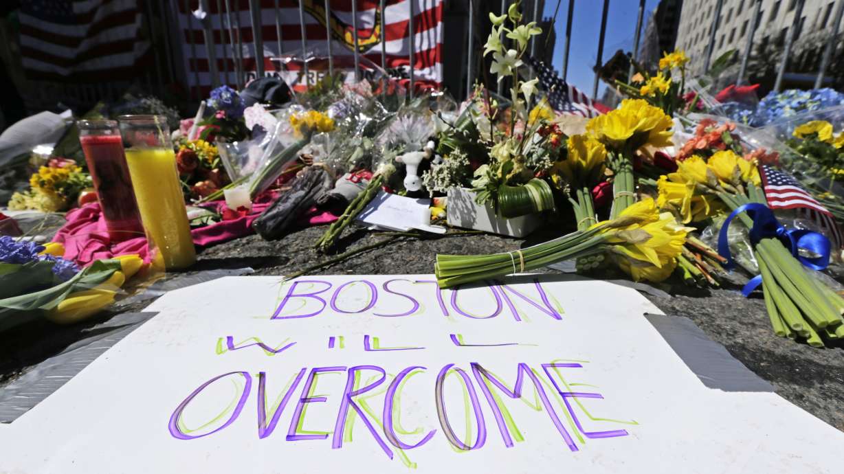 Flowers and signs adorn a barrier, two days after two explosions killed three and injured hundreds, near the finish line of the Boston Marathon at a makeshift memorial for victims and survivors of the bombing, April 17, 2013, in Boston.