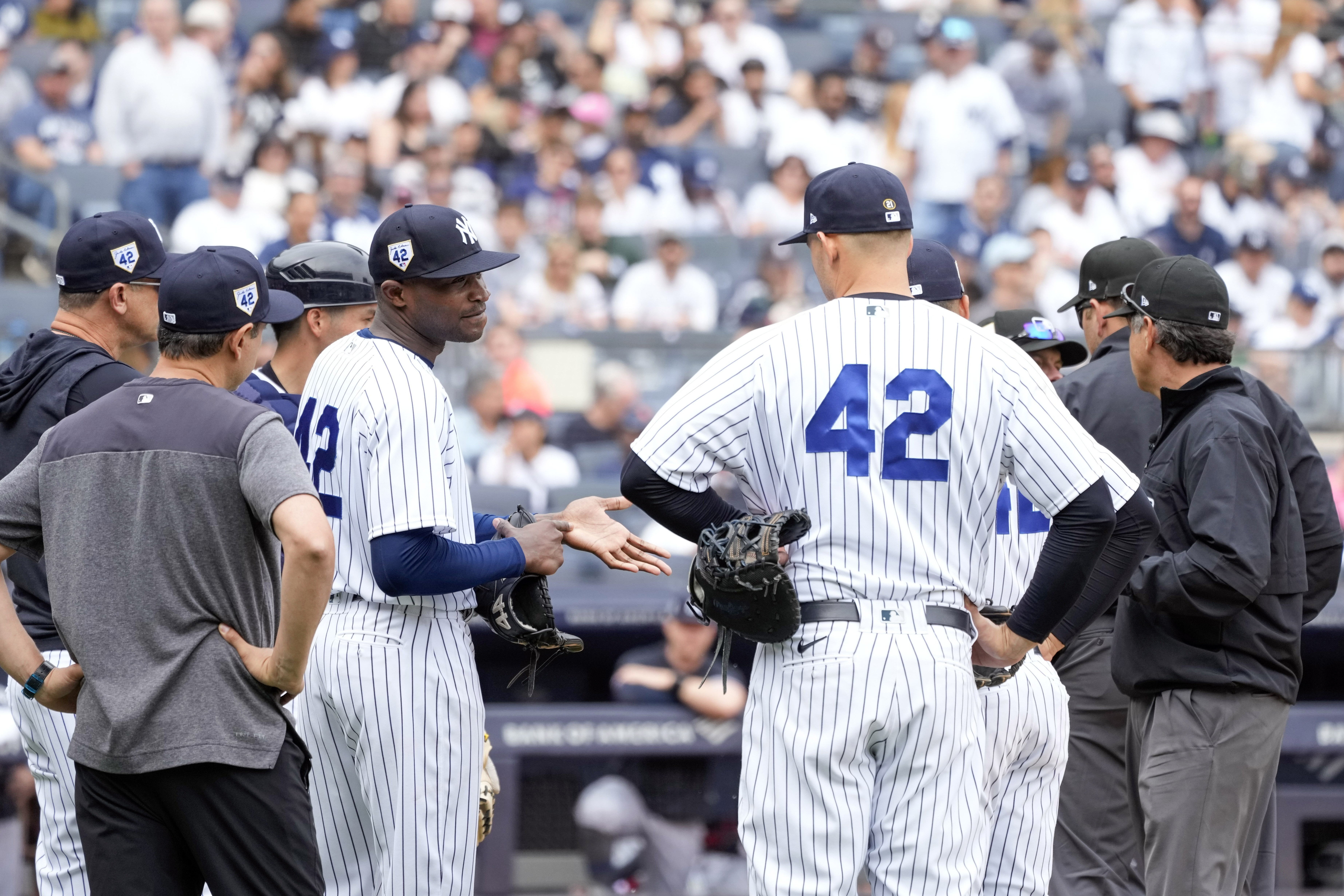 New York Yankees pitcher Domingo German, third from left, shows his hand to the umpires during the top of the fourth inning of a baseball game against the Minnesota Twins, Saturday, April 15, 2023, in New York.