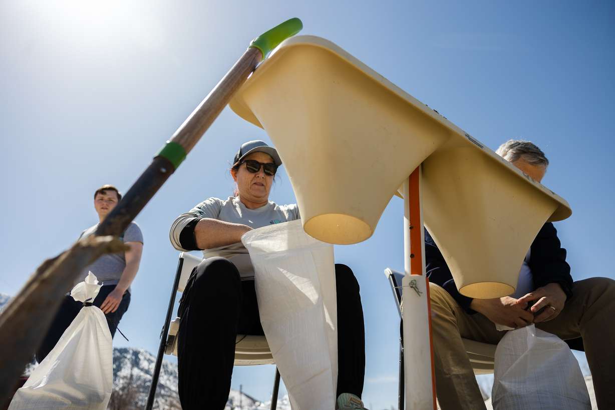 Susan Parkin prepares to tie a sandbag as volunteers fill up sandbags at Wasatch Public Works Yard in Millcreek on Saturday.