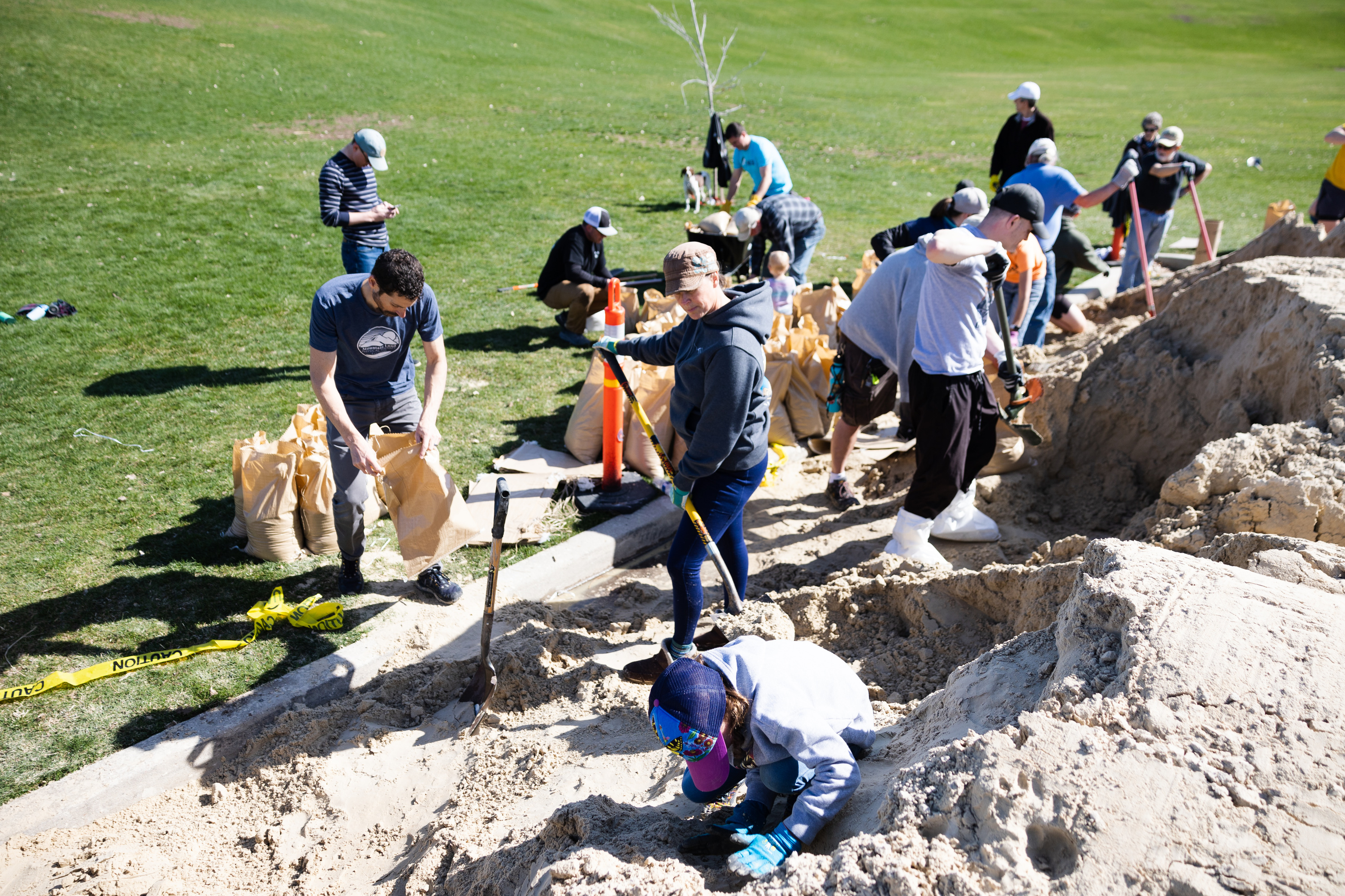 Josie Lobb, 8, pushes sand down as her parents Jason and Andrea Lobb shovel it, as volunteers fill up sandbags at Sugar House Park in Salt Lake City on April 15.