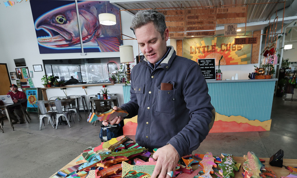 Artist Chris Peterson looks over painted fish at the Neighborhood Hive in Sugar House on April 4. Peterson is overseeing an art contest for the Utah Wildlife Federation.