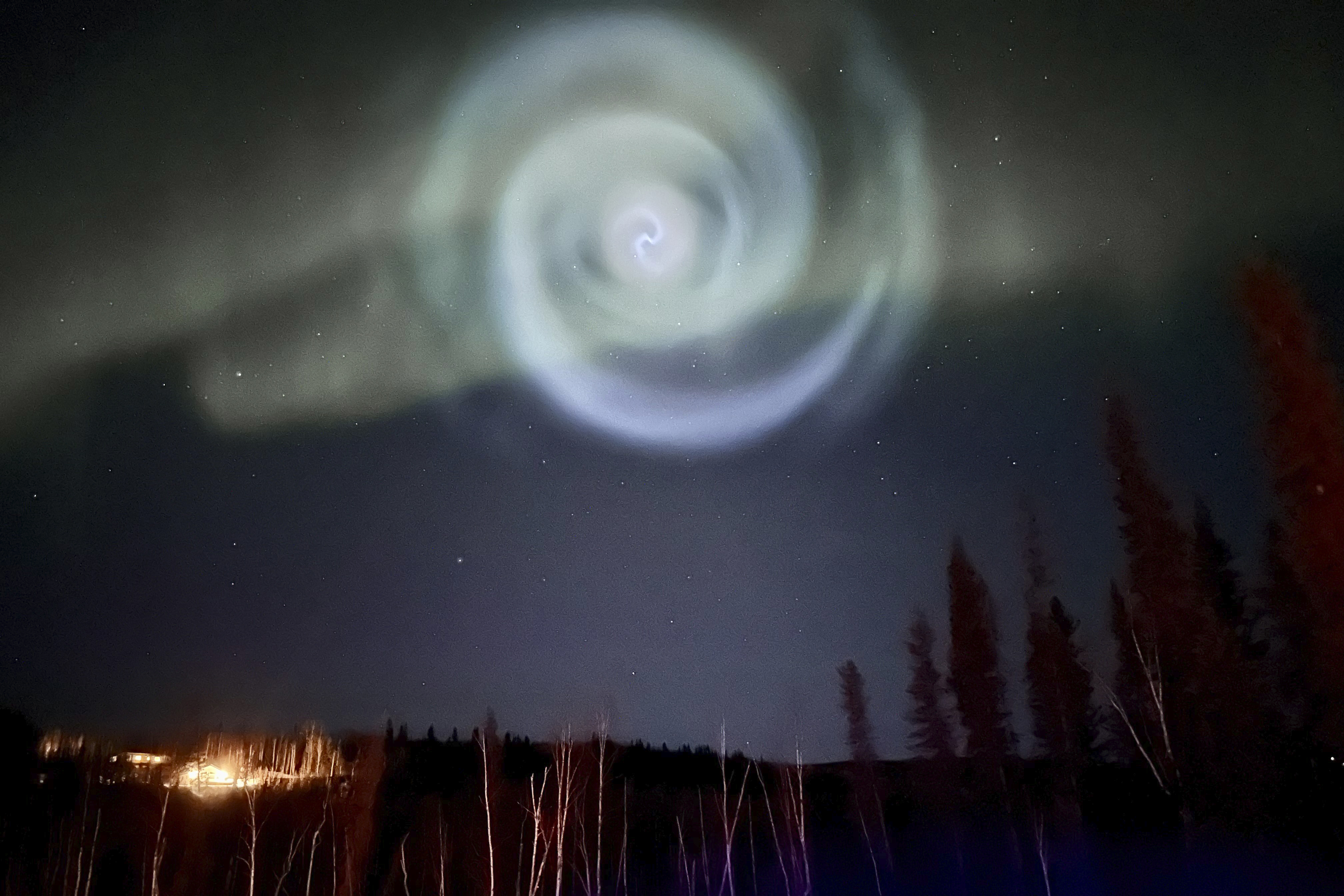 A light baby blue spiral resembling a galaxy appears amid the aurora for a few minutes in the Alaska skies near Fairbanks, Saturday. The spiral was formed when excess fuel that had been released from a SpaceX rocket that launched from California about three hours earlier turned to ice, and then the water vapor reflected the sunlight in the upper atmosphere.