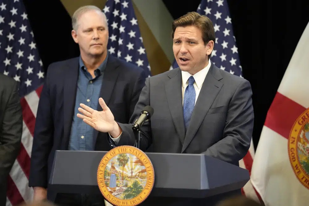 Florida Gov. Ron DeSantis, right, speaks at a news conference as Wilton Simpson, commissioner of agriculture, listens at the Reedy Creek Administration Building Monday, in Lake Buena Vista, Fla. DeSantis and Florida lawmakers ratcheted up pressure on Walt Disney World on Monday by announcing legislation that will use the regulatory powers of Florida government to exert unprecedented oversight on the park resort's rides and monorail.