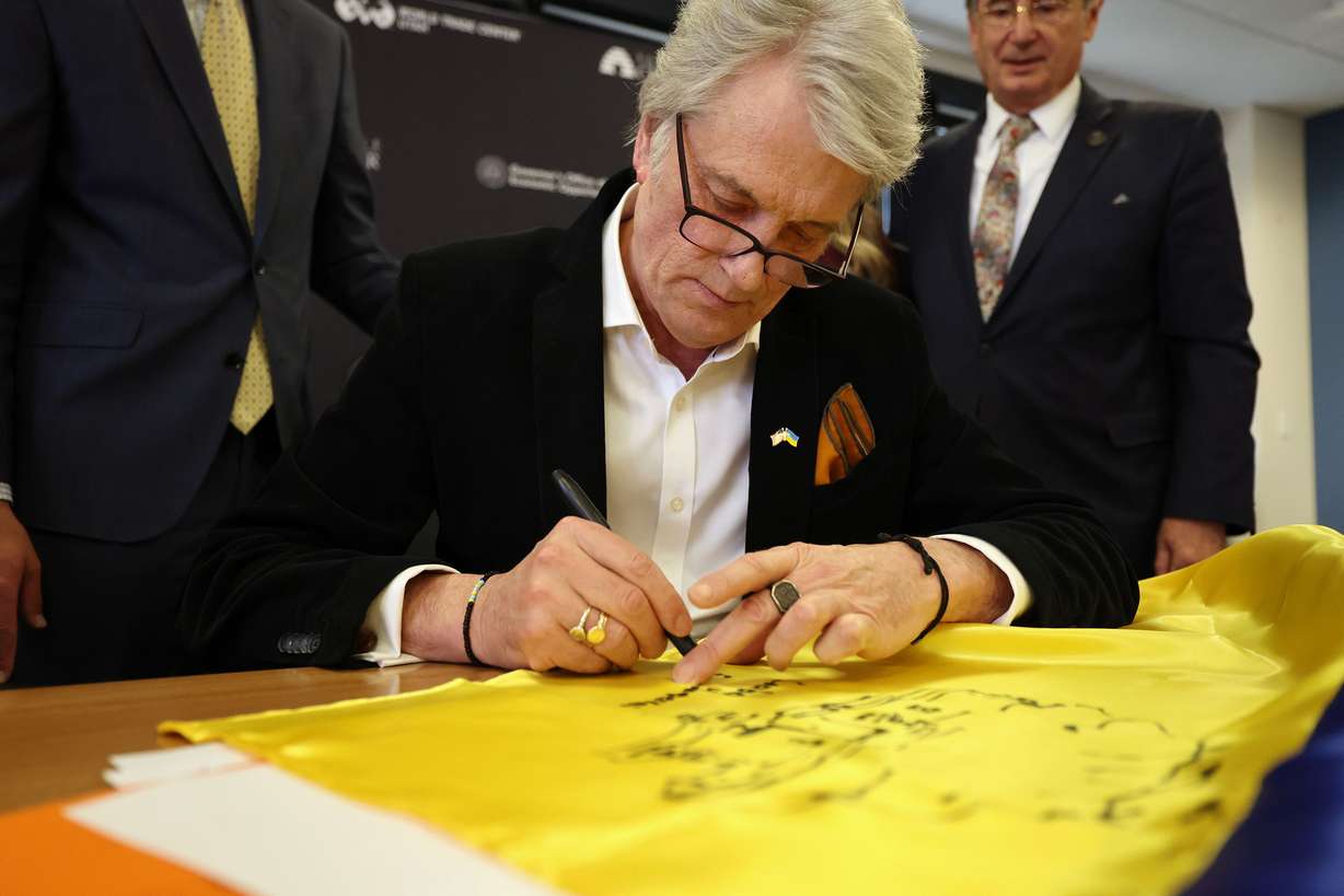 Former Ukrainian President Viktor Yushchenko draws a picture on a Ukrainian flag that he is gifted to the World Trade Center Utah in Salt Lake City on Monday.