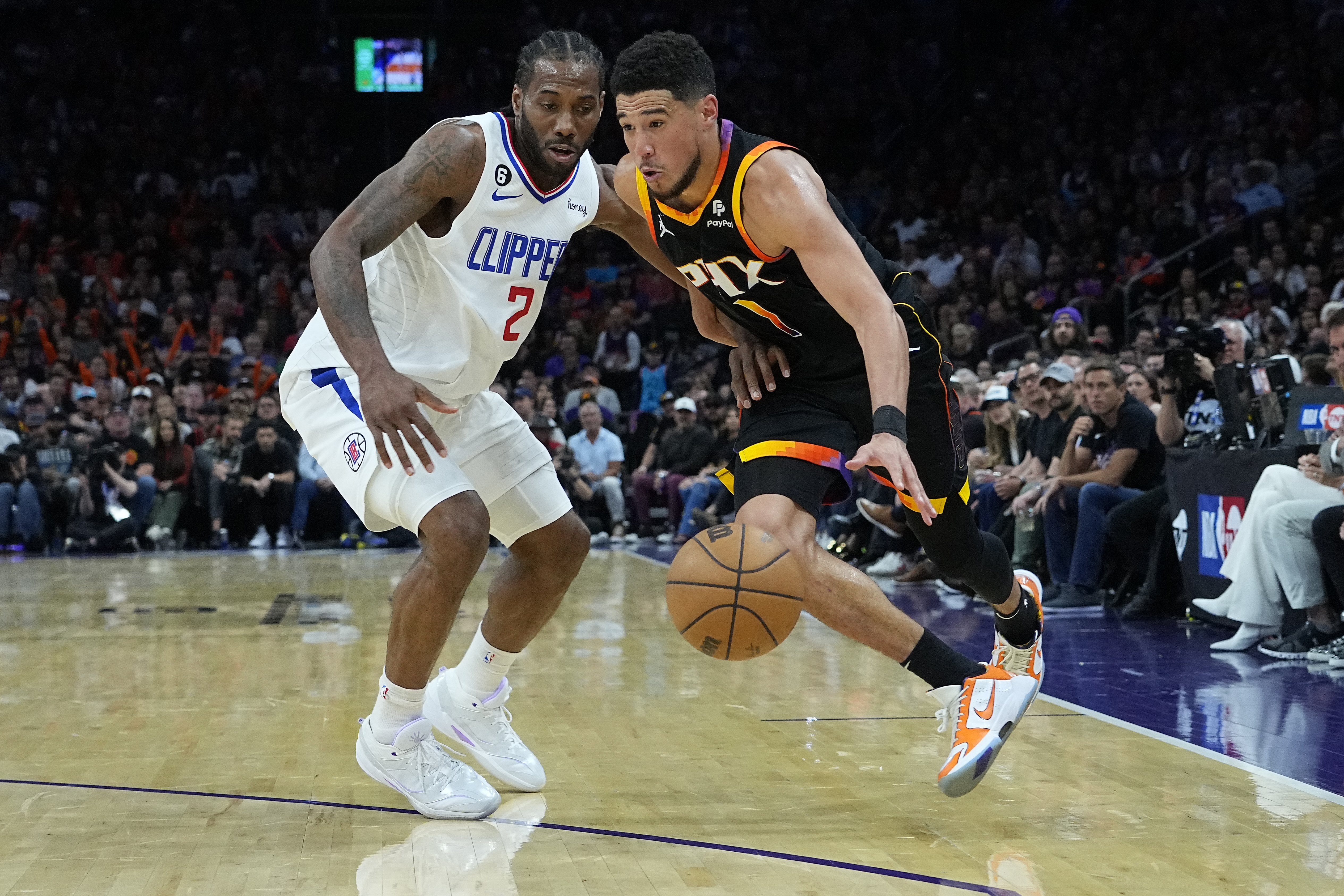 Phoenix Suns guard Devin Booker (1) drives on Los Angeles Clippers forward Kawhi Leonard (2) during the second half of Game 2 of a first-round NBA basketball playoff series, Tuesday, April 18, 2023, in Phoenix. 