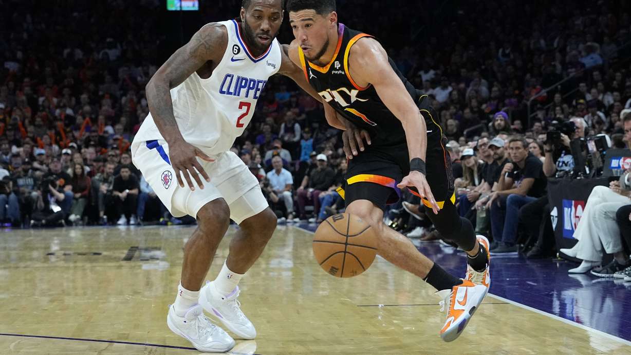 Phoenix Suns guard Devin Booker (1) drives on Los Angeles Clippers forward Kawhi Leonard (2) during the second half of Game 2 of a first-round NBA basketball playoff series, Tuesday, April 18, 2023, in Phoenix.