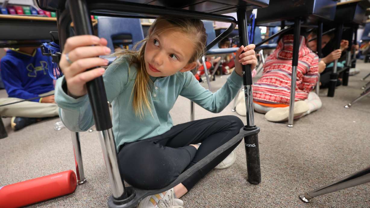 Fourth grader Evelyn Dunn sits under her desk while holding onto the desk legs during the Great Utah Shakeout, the statewide earthquake preparedness drill, at Canyon View Elementary School in Cottonwood Heights on Thursday.