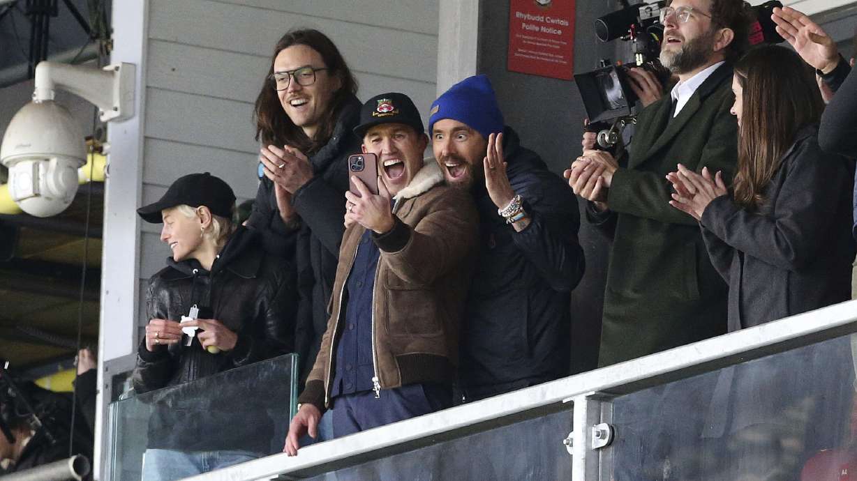FILE - Wrexham owners Ryan Reynolds, center right, and Rob McElhenney, center left, react during the National League match between Wrexham and Notts County at the Racecourse Ground, Wrexham, Wales, Monday April 10, 2023. It's hard to imagine that even A-list owners Ryan Reynolds and Rob McElhenney anticipated the unscripted drama created by this unlikely union between Tinseltown and Wrexham, a former mining town in Wales.