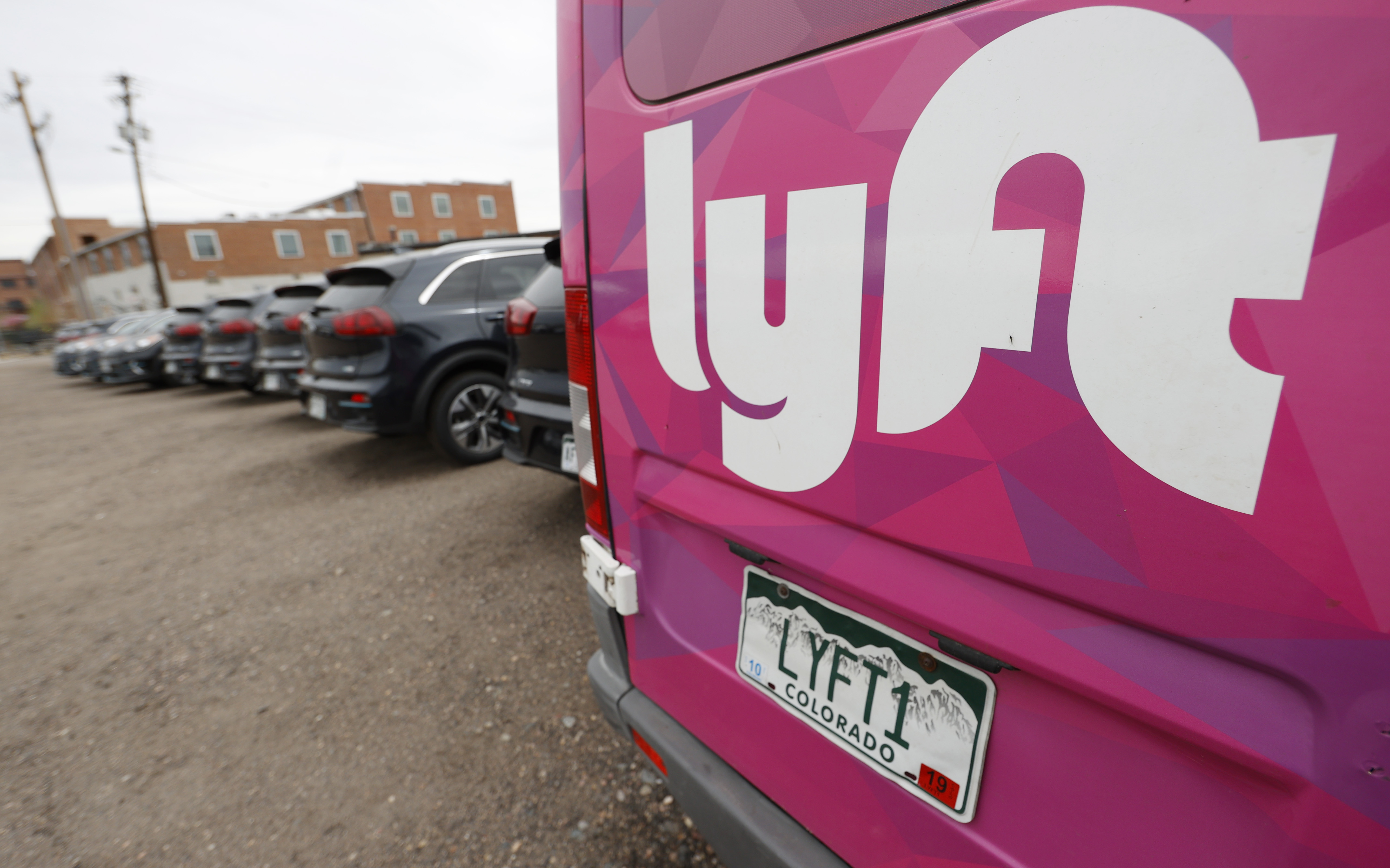 A Lyft ride-hailing vehicle is parked near Empower Field at Mile High in Denver on April 30, 2020. Lyft is preparing to lay off hundreds of employees. 