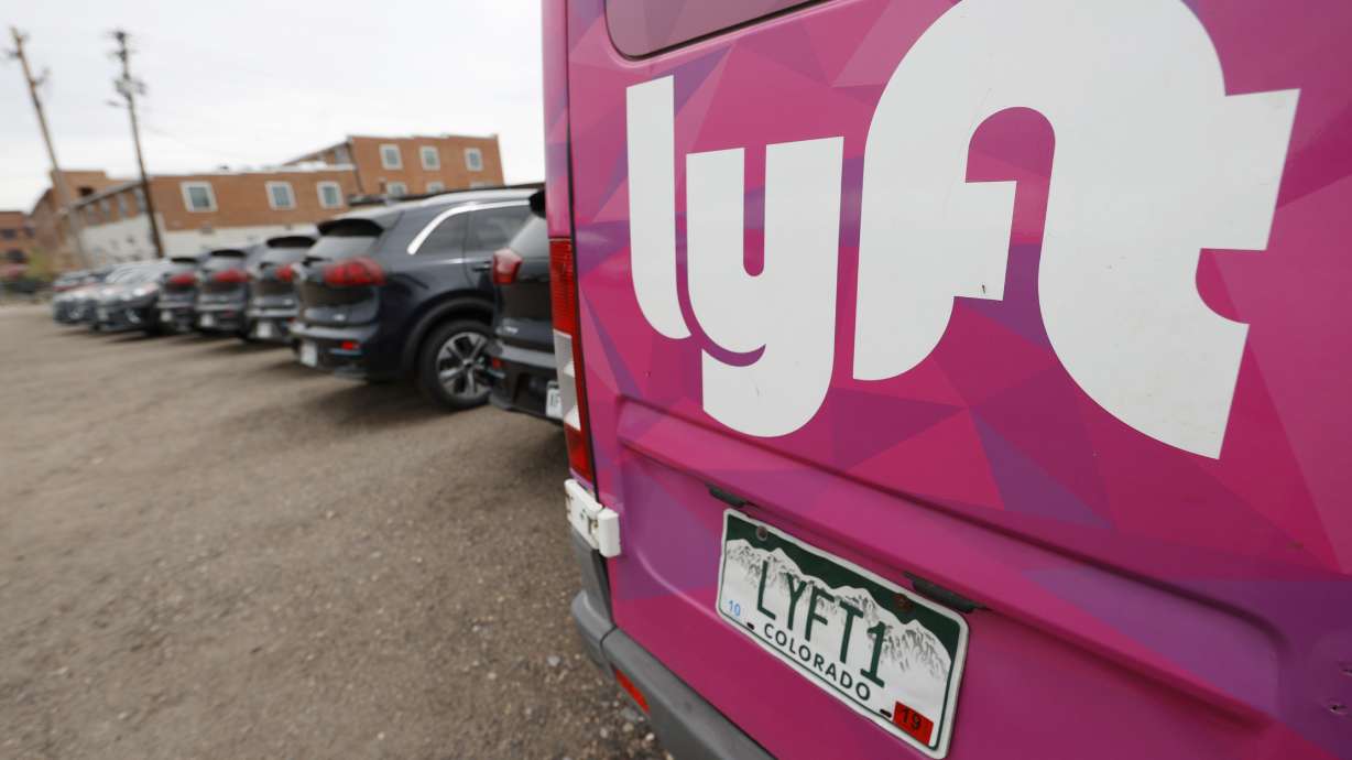 A Lyft ride-hailing vehicle is parked near Empower Field at Mile High in Denver on April 30, 2020. Lyft is preparing to lay off hundreds of employees.