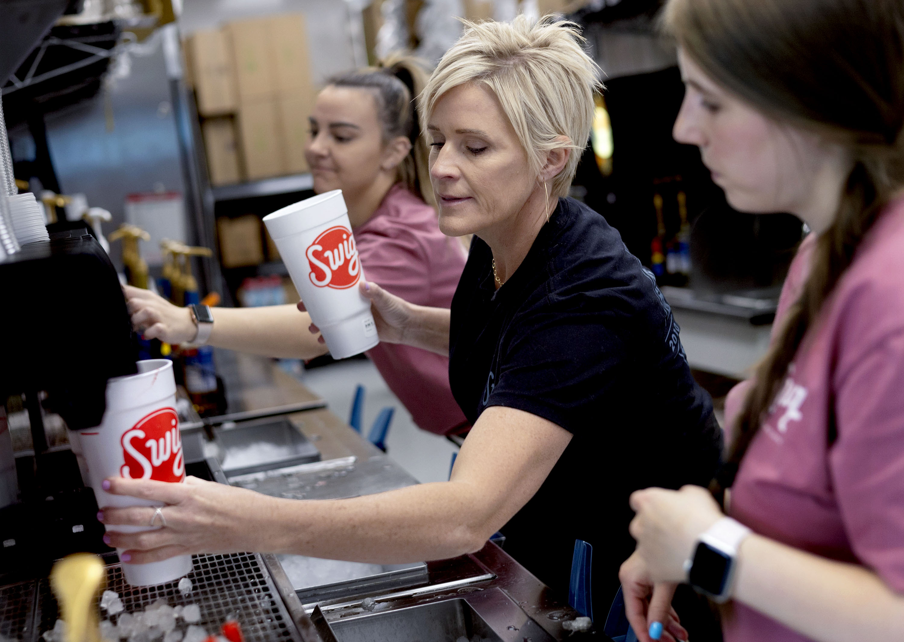Tasia Alston, Swig founder Nicole Tanner and Hannah McClure make drinks at Swig in Sandy on Friday. Swig's one-day "50 for 50" event Friday featured 50-cent drinks and cookies to celebrate the 50th store location opening next week.